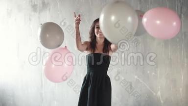 快乐的年轻女子抛出气球和微笑。 节日的气氛。 庆祝的感觉。 慢动作